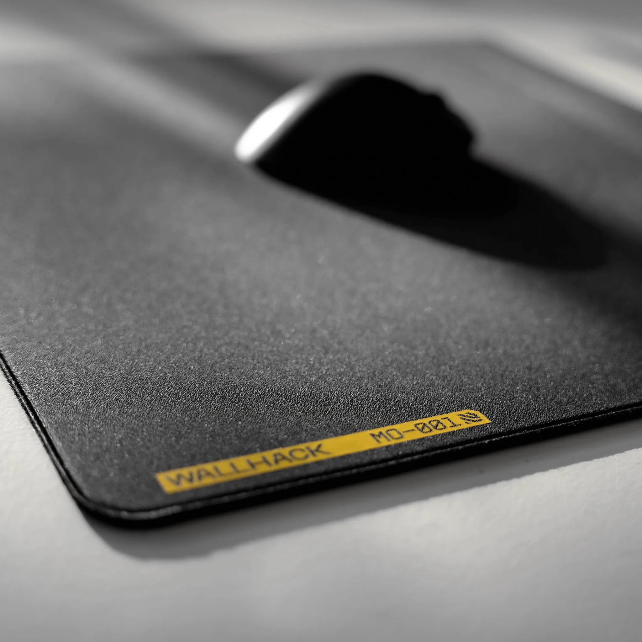 Black mouse pad with 'Wallhack' branding on a gray surface
