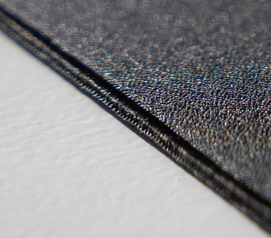 A close up shot of a black mousepad edge stiching showing Crepe Weave Fabric