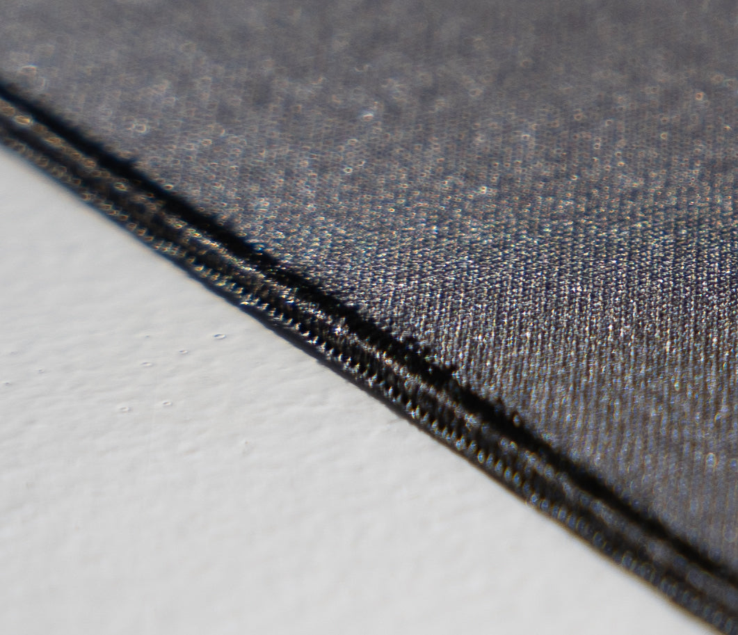 Close up of a black mouse pad stitched edges showing pique knit fabric