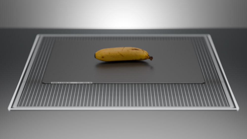 A yellow banana ontop of a black colored glass mouse pad